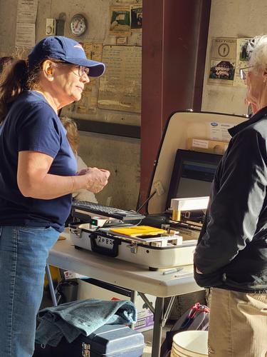 A women (Liz Maxwell) talking to a person with lab equipment in the background. Photo by Brent Roeder.