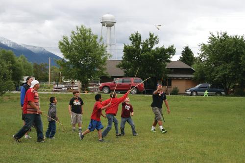 A group of men and youth raise sticks in their hands during a double ball stick game. 