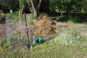 The wire bin is constructed from an eleven-foot section of four-foot tall fencing, which gives a volume slightly larger than one cubic yard.  Inputs include straw (brown), grass clippings and garden debris (greens), topsoil, and water. A pitchfork makes material handling easy.