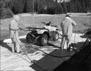 Two men power washing an ATV outdoors