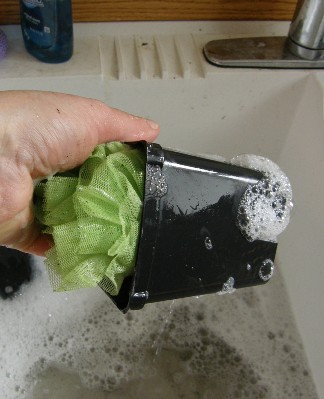 A small plastic pot being washed in a sink