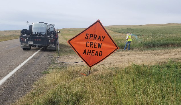 A spray crew on the side of a highway spraying to manage noxious weeds