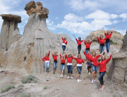A group of women in red shirts pose among the geological formations in Makoshika State Park