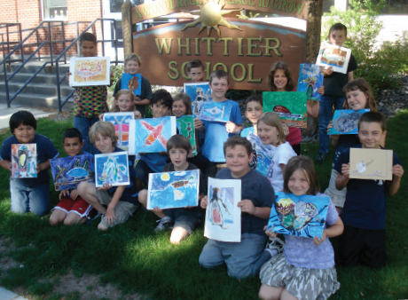 A group of young school children in front of a sign that reads 