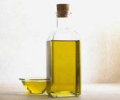 A bottle of oil with a small dish of oil next to it