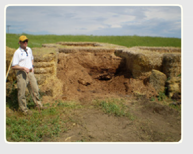 A man standing in the field near a livestock composting operation