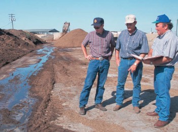 Three men standing near a muddy stream
